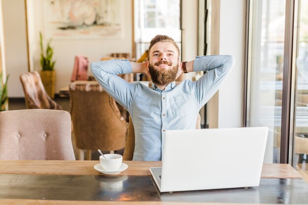 Homem feliz, relaxante, em, caf�, com, xícara café, e, laptop, escrivaninha