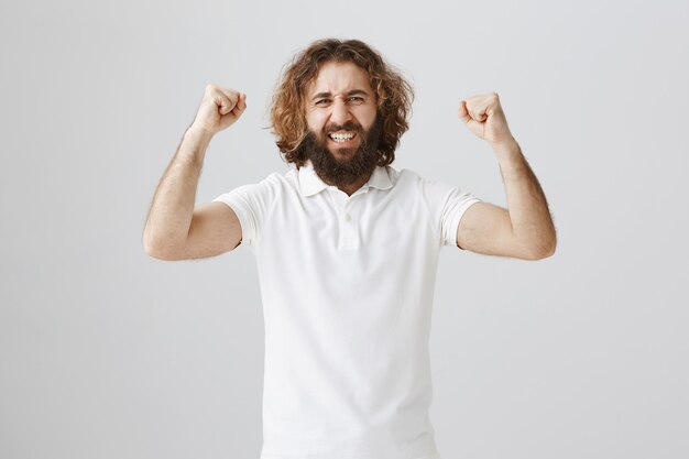 Homem feliz triunfante do Oriente Médio erguendo as mãos em um gesto de sim, comemorando a vitória