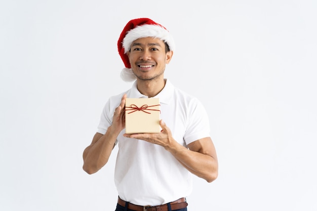 Homem feliz usando chapéu de papai noel e mostrando a caixa de presente