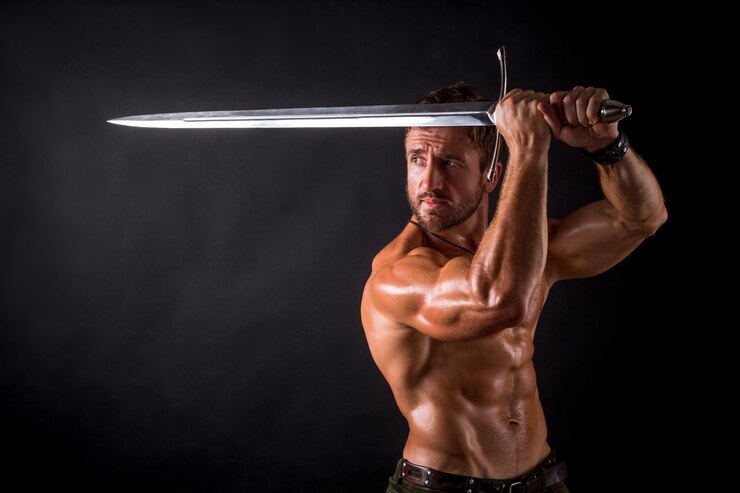 Foto grátis homem fisiculturista posando com uma espada isolada em fundo preto homem sem camisa sério demonstrando seu corpo mascular