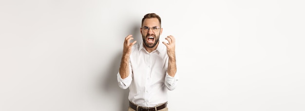 Homem frustrado e irritado gritando de raiva apertando as mãos furiosas sobre fundo branco