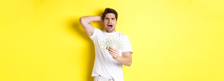 Foto grátis homem frustrado segurando dinheiro gritando e em pânico em pé sobre fundo amarelo