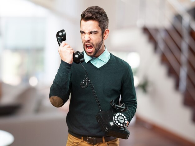 Homem furioso gritando com um telefone velho