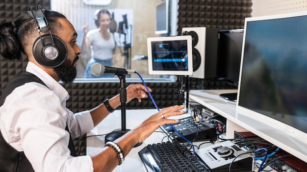 Homem gravando uma mulher cantando em uma estação de rádio