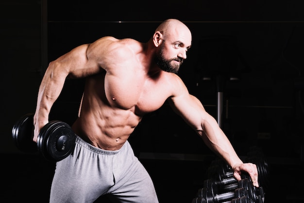 Homem grave levantando dumbbell pesado