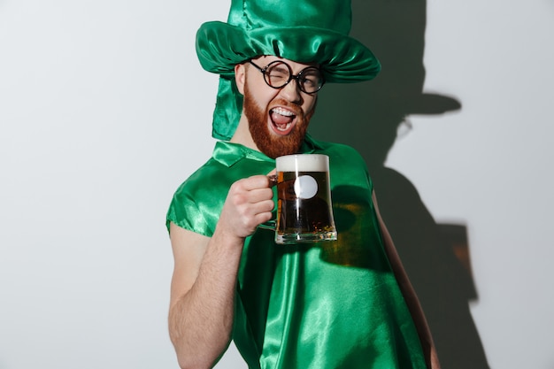 Homem gritando bêbado em traje de st.patriks segurando xícara