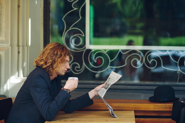 Homem hipster bebendo café durante a leitura