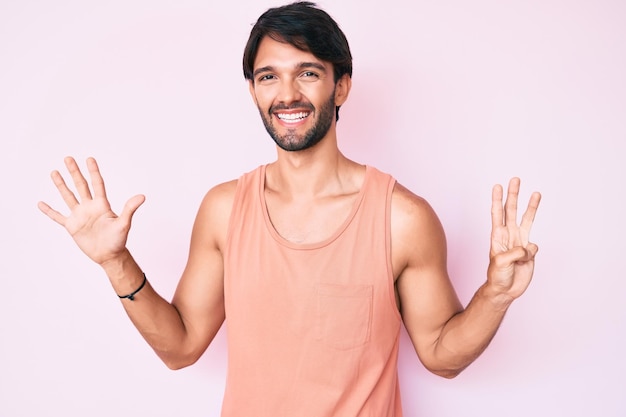 Foto grátis homem hispânico bonito vestindo roupas casuais mostrando e apontando para cima com os dedos número oito enquanto sorria confiante e feliz