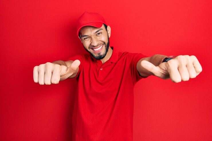Foto grátis homem hispânico com barba vestindo uniforme de entrega e boné aprovando fazendo gesto positivo com mão polegares para cima sorrindo e feliz pelo gesto de vencedor de sucesso