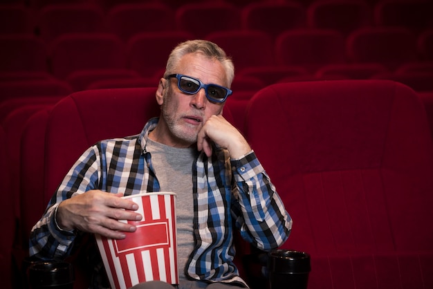 Homem idoso assistindo filme no cinema