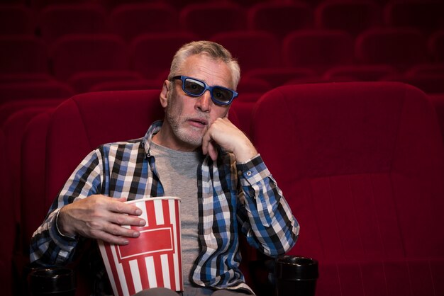 Homem idoso assistindo filme no cinema