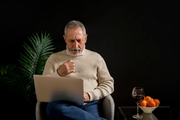 Homem idoso pensativo com laptop