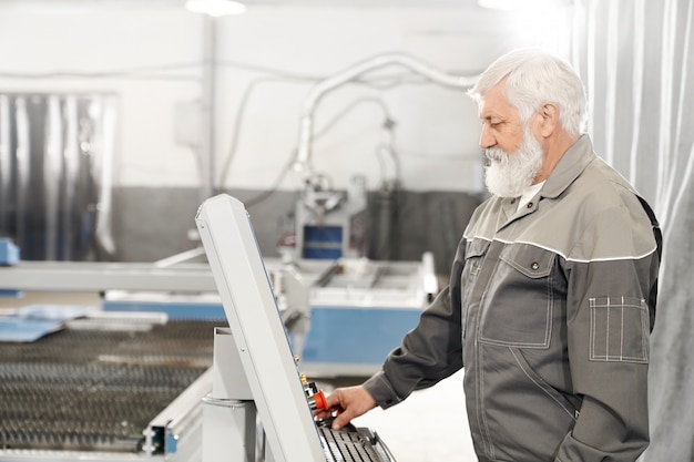 Foto grátis homem idoso que trabalha com a máquina de corte a laser na fábrica.