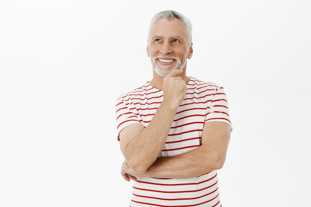 Foto grátis homem idoso sorridente e pensativo, olhando no canto superior esquerdo com uma expressão satisfeita