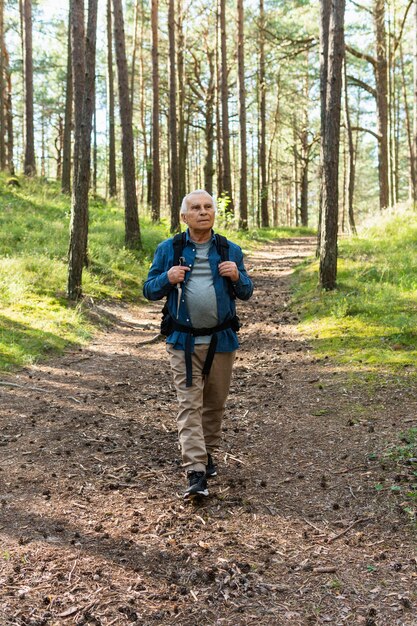 Homem idoso viajando com mochila na natureza