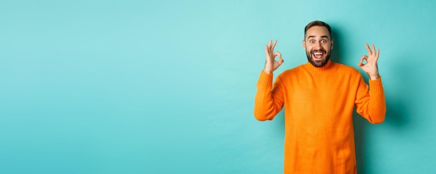 Foto grátis homem impressionado elogiando algo incrível mostrando sinais de aprovação e parecendo espantado em pé em laranja sw