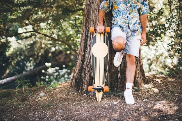 Homem, inclinar-se, árvore, com, skateboard