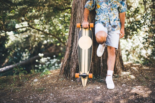 Homem, inclinar-se, árvore, com, skateboard