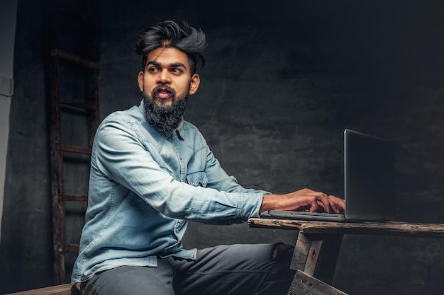 Foto grátis homem indiano barbudo elegante trabalhando com laptop.