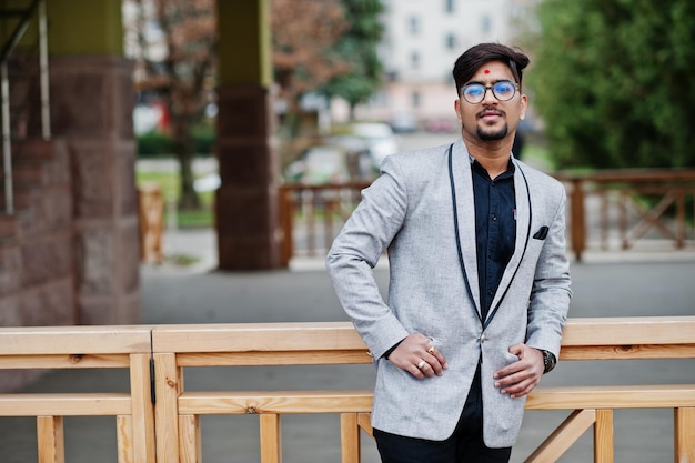 Homem indiano elegante com bindi na testa e óculos usam terno cinza posado ao ar livre