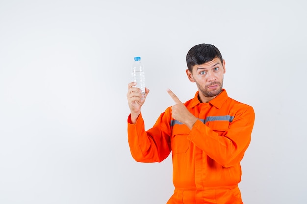 Homem industrial de uniforme, apontando para a garrafa de água, vista frontal.