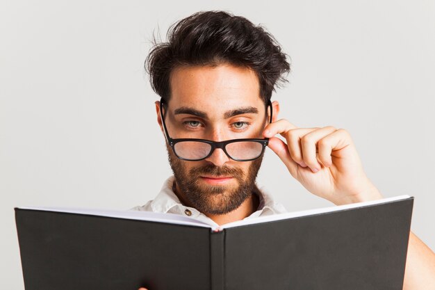 Homem intelectual posando com óculos e livro