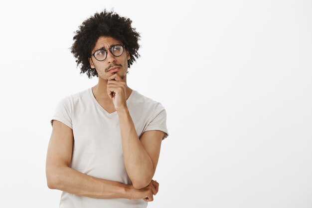 Homem inteligente pensativo de óculos, fazendo suposições, ponderando. homem pensando e olhando o espaço vazio do canto superior direito para o seu logotipo