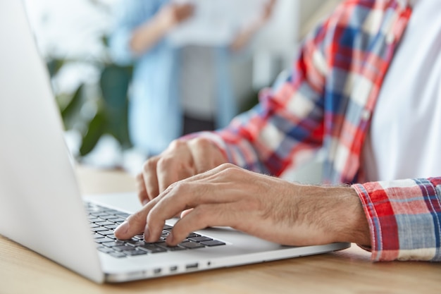 Homem irreconhecível trabalha em um laptop portátil moderno e instala um novo aplicativo