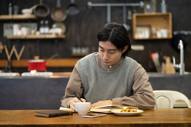 Homem japonês escrevendo em um caderno em um restaurante