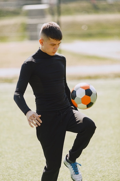 Foto grátis homem joga socerl no parque. torneio de mini futebol. cara em um traje esporte preto.