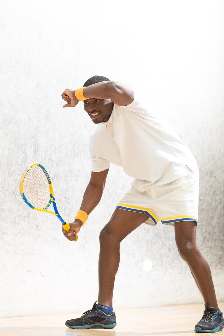 Foto grátis homem jogador de squash tocando sua testa após grande jogo no squash homem bonito segurando raquete e sorrindo