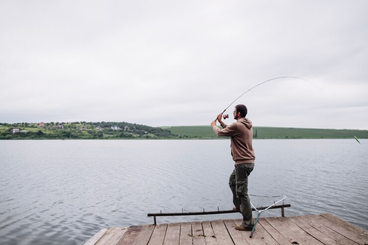 Foto grátis homem jogando linha de pesca no lago