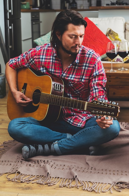 Homem jovem, afinando, violão, sentar chão