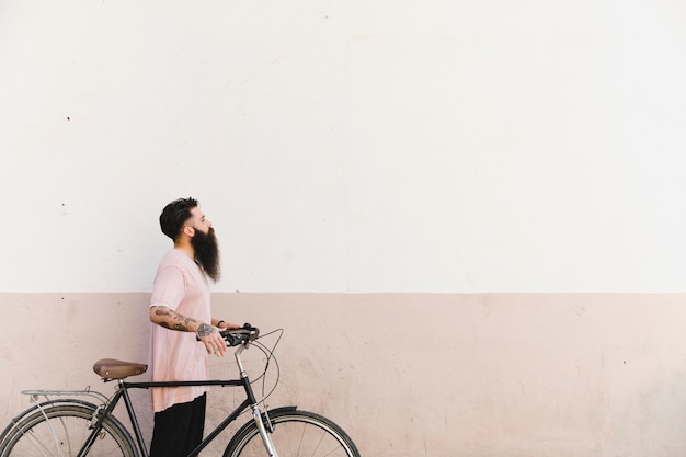 Homem jovem, andar, com, bicicleta, contra, parede pintada