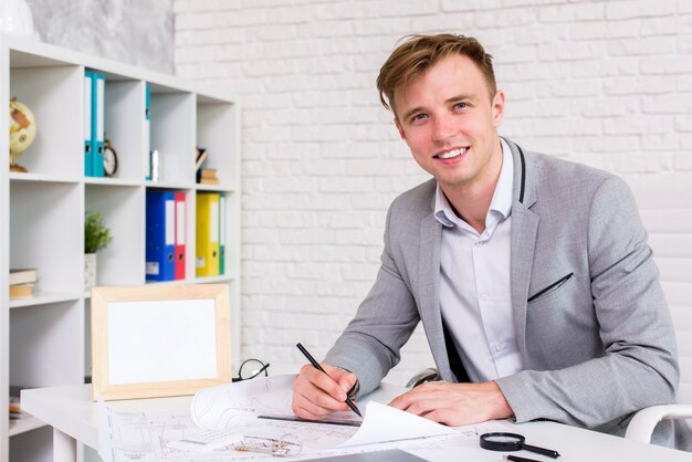 Homem jovem, assinando, um, documento, enquanto, olhando câmera