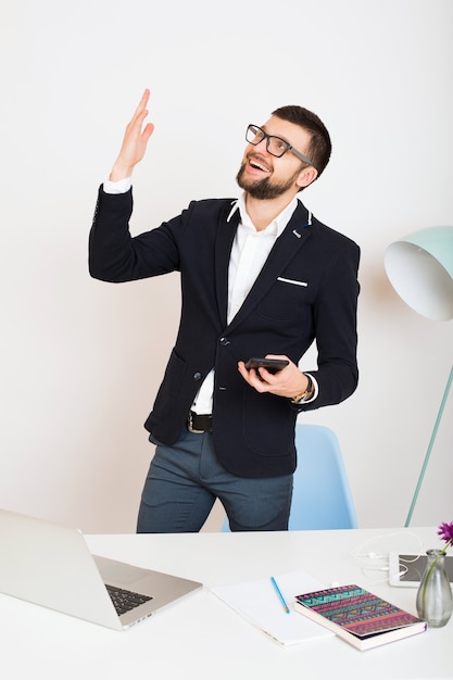 Homem jovem bonito elegante hipster com jaqueta jovem na mesa do escritório