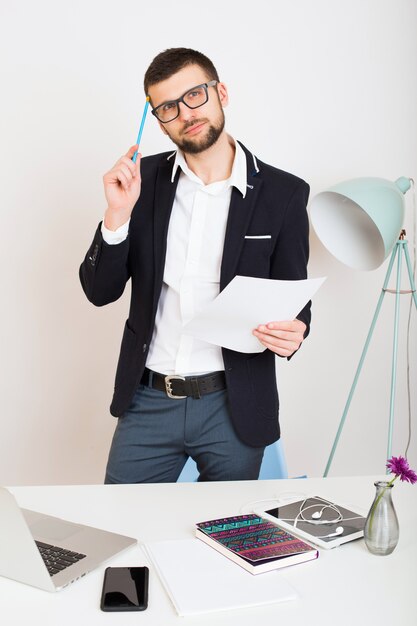 Homem jovem bonito elegante hipster em jaqueta preta trabalhando na mesa do escritório, estilo empresarial, camisa branca, isolado, laptop, inicializar, local de trabalho, pensamento, documentos