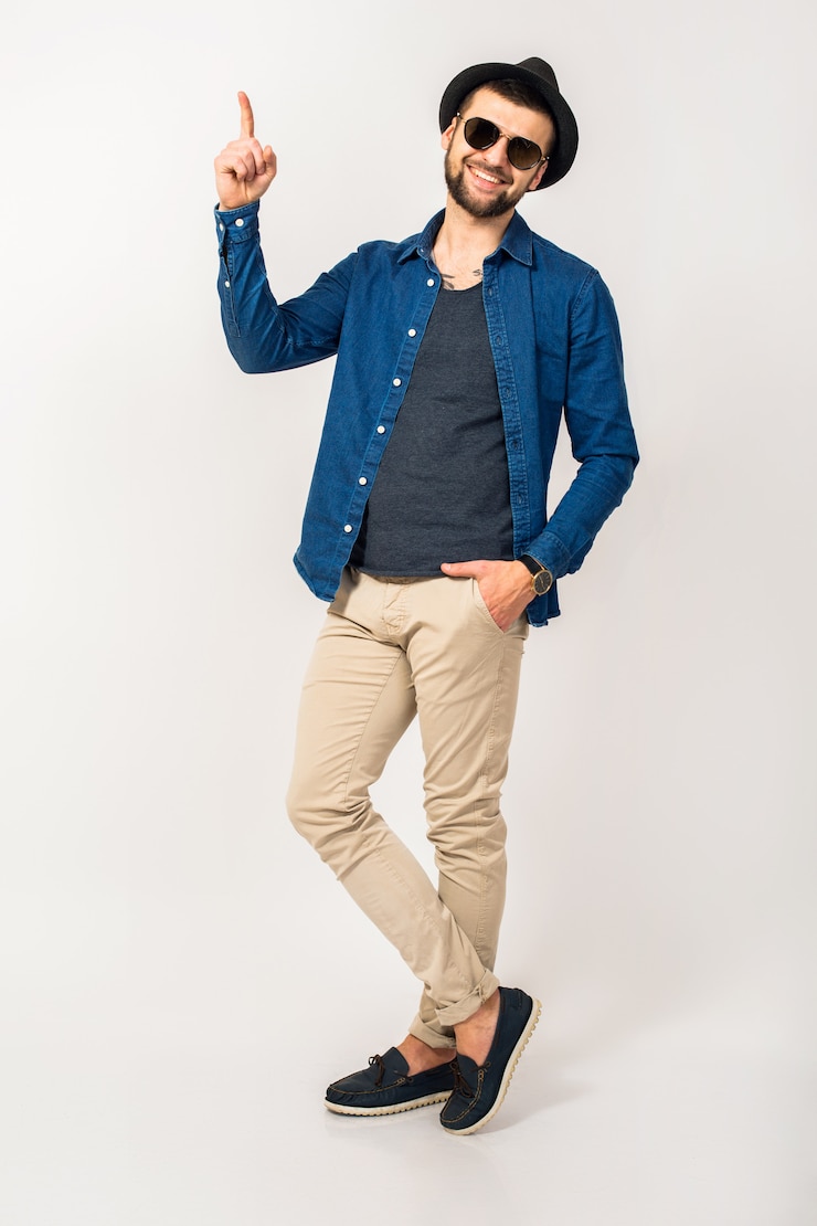 Foto grátis homem jovem bonito hippie, roupa de estilo moderno, camisa jeans, calças, óculos de sol, chapéu, isolado, pulando, alegre, dedo apontando