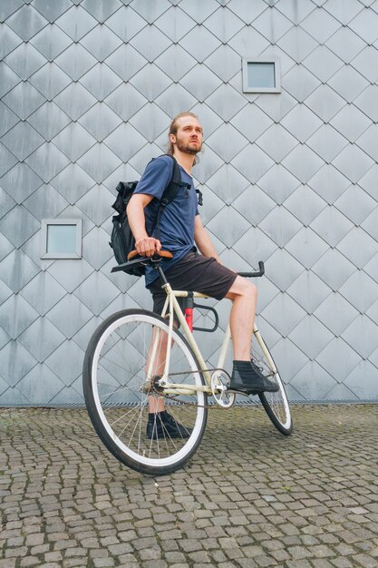 Homem jovem, carregar, mochila, bicicleta equitação, em, ao ar livre