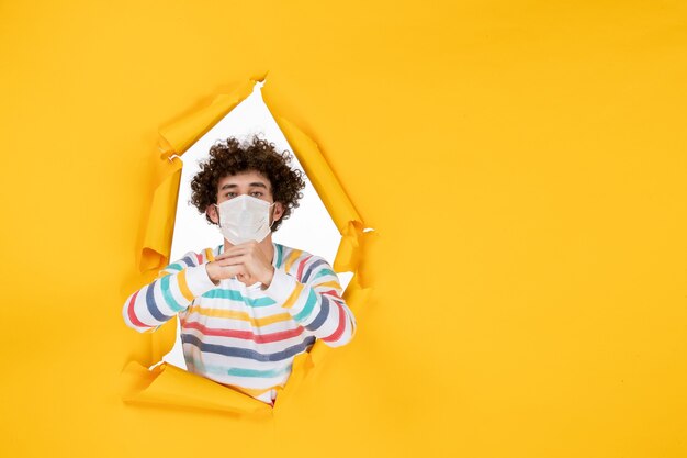 Homem jovem com máscara estéril em frente a frente com vírus covidêmico da foto colorida da saúde amarelo - vírus pandêmico humano