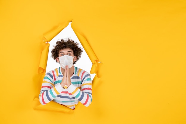 Foto grátis homem jovem com máscara estéril em frente a frente com vírus covidêmico da foto colorida da saúde amarelo - vírus pandêmico humano