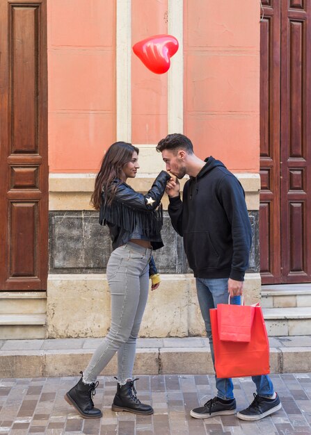 Homem jovem, com, pacotes, beijando, mão, de, mulher, e, voando, balloon