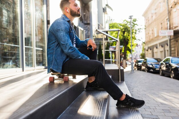 Homem jovem, com, skateboard, sentando, ligado, escadaria