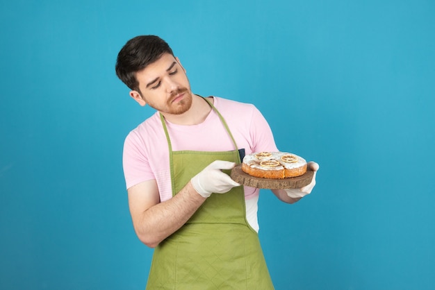 Homem jovem confiante segurando bolo caseiro e olhando para ele.