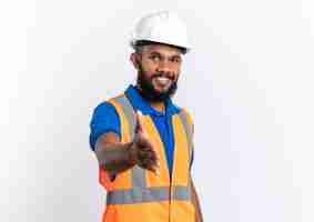 Foto grátis homem jovem construtor afro-americano de uniforme com capacete de segurança segurando a mão, isolado no fundo branco com espaço de cópia.