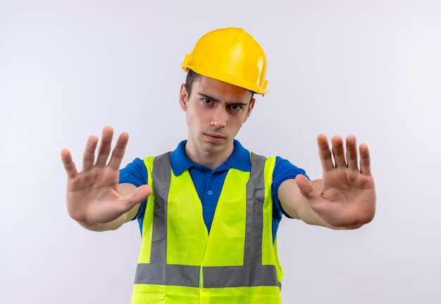 Homem jovem construtor usando uniforme de construção e capacete de segurança para com raiva