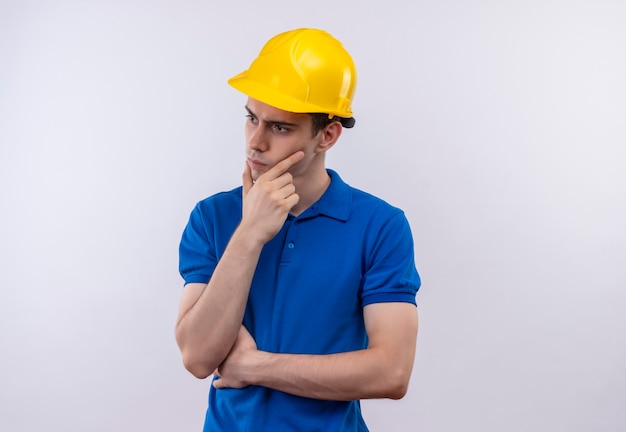 Homem jovem construtor usando uniforme de construção e capacete de segurança pensando