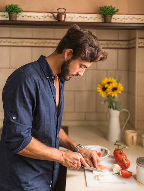 Homem jovem, corte, fatias, de, rabanete, em, contador cozinha