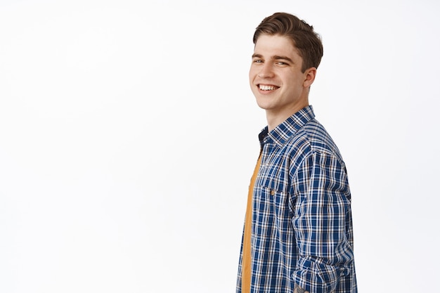 Foto grátis homem jovem e bonito, caucasiano, olhando para a câmera feliz e despreocupado, sorrindo satisfeito, casual em uma roupa de verão em branco