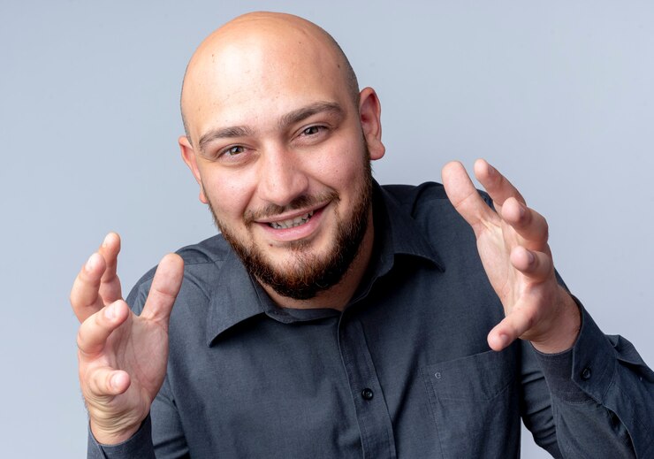 Foto grátis homem jovem e careca sorridente de call center de mãos dadas, olhando para frente, isolado na parede branca